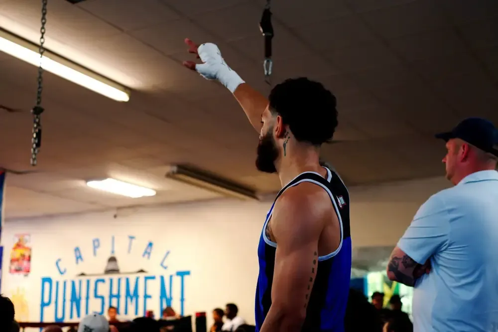 A boxer raises a wrapped hand to the crowd inside the hall